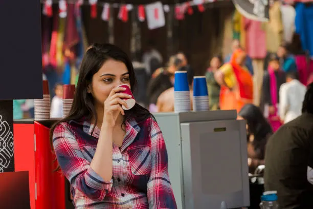 young-woman-drinking-coffee-at-street-market-stock-photo